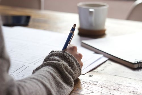 person-writing-on-brown-wooden-table-near-white-ceramic-mug-s9CC2SKySJM.jpg