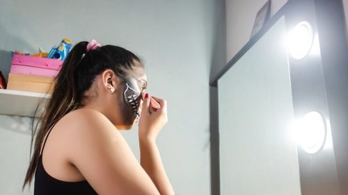 close-up-view-girl-concentrating-making-up-artistic-skull-halloween-her-room_311379-628.jpg