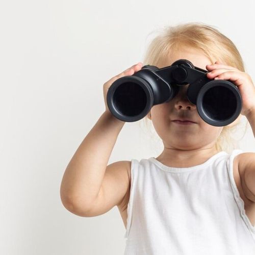 blond-child-looking-through-binoculars-light-background-studio-banner_164357-10820.jpg