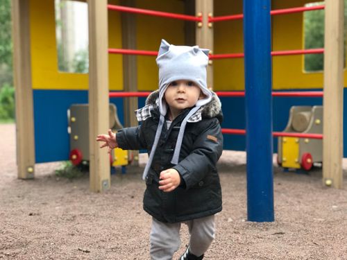 child-in-black-jacket-and-white-cap-standing-near-yellow-blue-and-red-playground-during-daytime-i8u-ll9039k.jpg