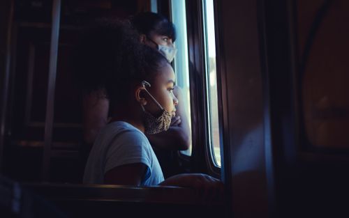 a-young-girl-looking-out-the-window-of-a-train-cgNOHL12gAg.jpg